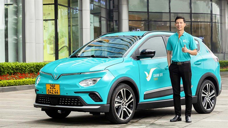 Conductor junto a un taxi eléctrico verde turquesa de la compañía Green SM en Vietnam