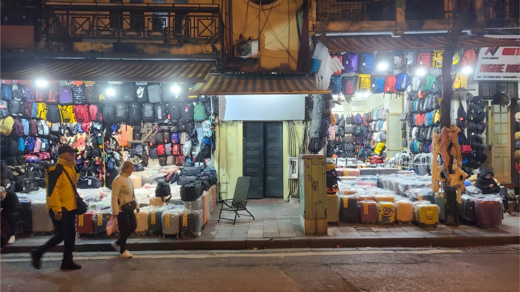 Calle del Barrio Viejo de Hanoi con varias tiendas de mochilas, maletas y accesorios de viaje por la noche