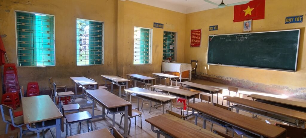 Aula vacía de una escuela pública en una zona rural de Vietnam, con bandera vietnamita y retrato de Ho Chi Minh