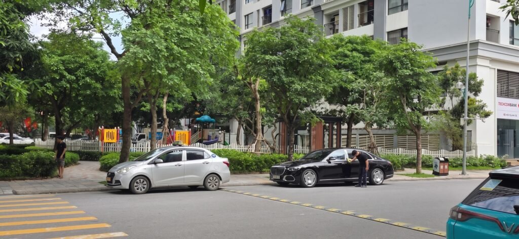 Coche de lujo Mercedes-Maybach aparcado en una zona residencial moderna de Hanoi junto a un taxi y una zona de juegos