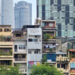 Contraste entre casas tradicionales vietnamitas y rascacielos modernos en Ho Chi Minh