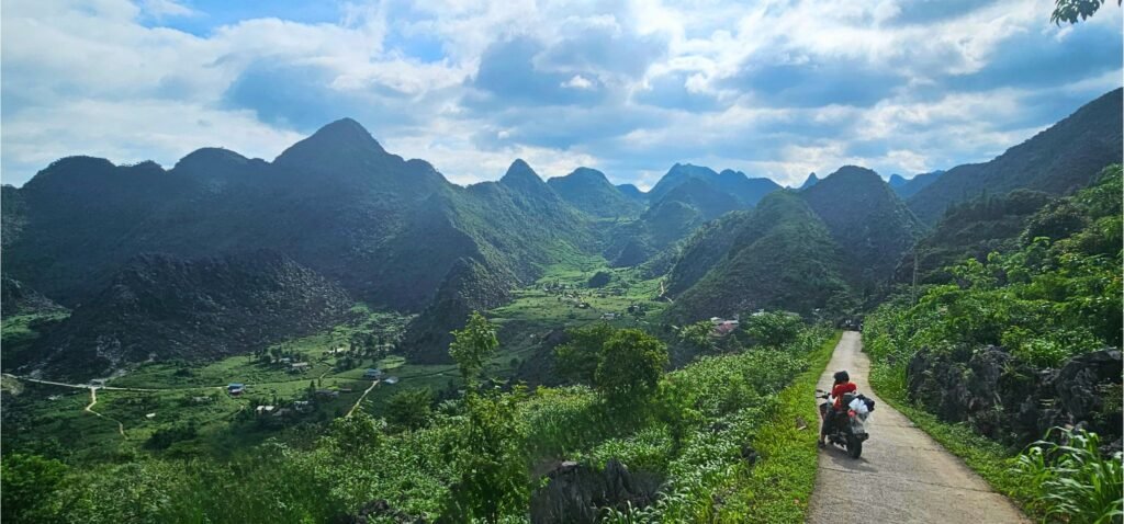 Persona recorriendo en moto una carretera de montaña entre los paisajes kársticos de Ha Giang, Vietnam