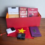 Caja de regalo roja con guías de viaje de Vietnam, el diario de Dang Thuy Tram, una GoPro, una batería portátil y una funda de pasaporte