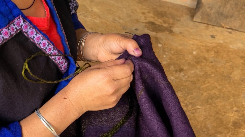 Mujer hmong cosiendo tejido tradicional hecho con hilo de cáñamo