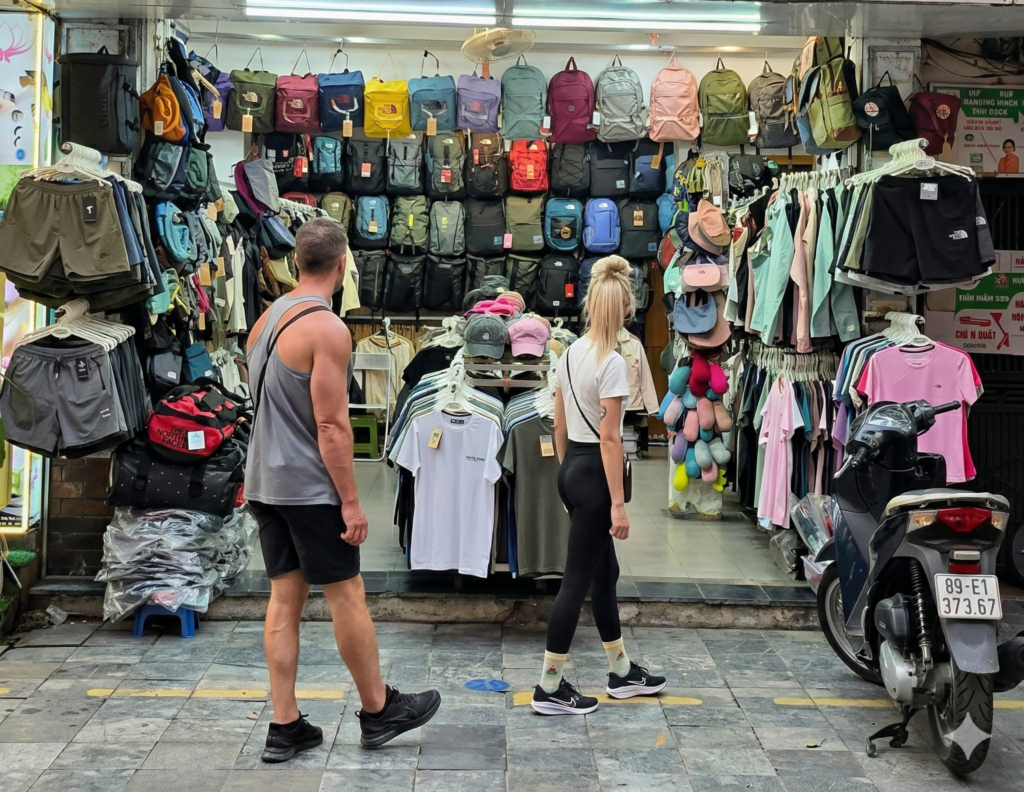 Tienda de mochilas y ropa The North Face en el Barrio Viejo de Hanoi con turistas mirando los productos