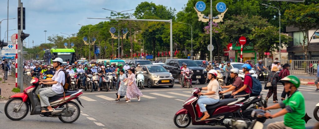 Tráfico denso de motos, coches y peatones en una avenida de Hanoi durante la hora punta