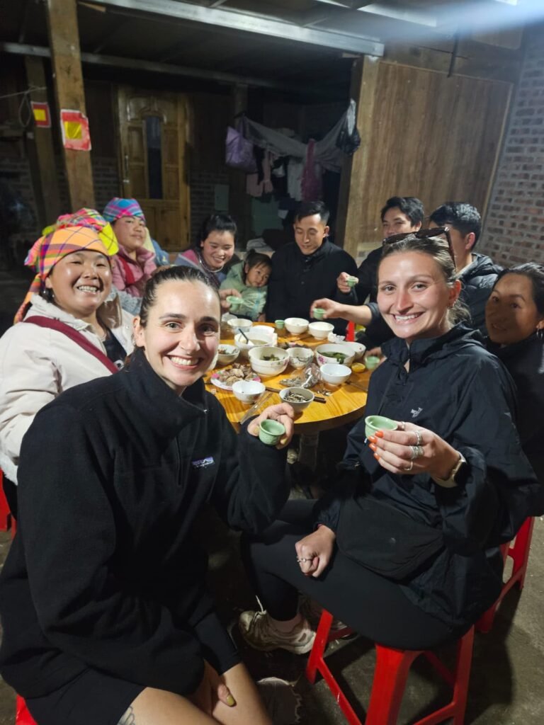 Viajeras y familia local brindando con licor de arroz durante la cena en casa de Mama Mao, Sapa