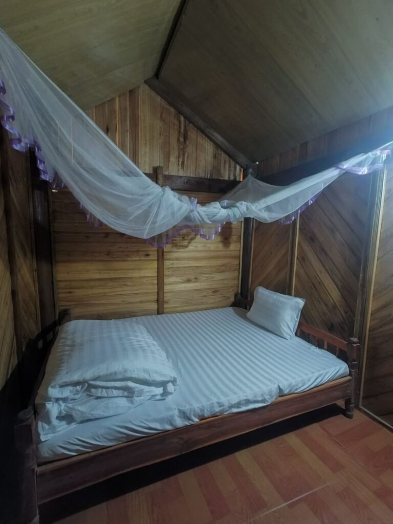 Habitación de madera con cama y mosquitera en el alojamiento de Mama Mao, Sapa