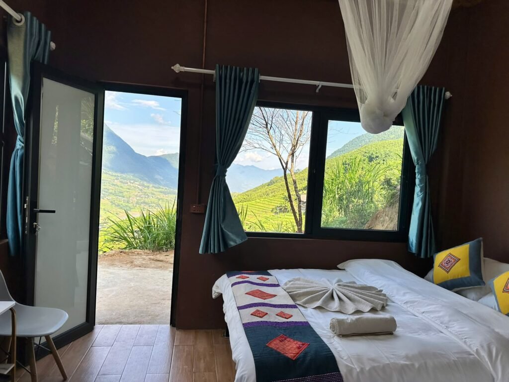 Habitación con cama, mosquitera y ventanales con vistas a los arrozales en el alojamiento de Dinh Sapa Trekking Adventures