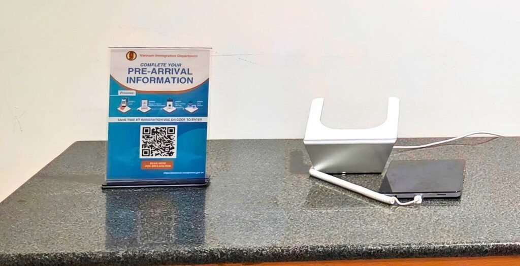 Cartel con QR y tablet para rellenar la declaración de entrada en el aeropuerto de Hanoi