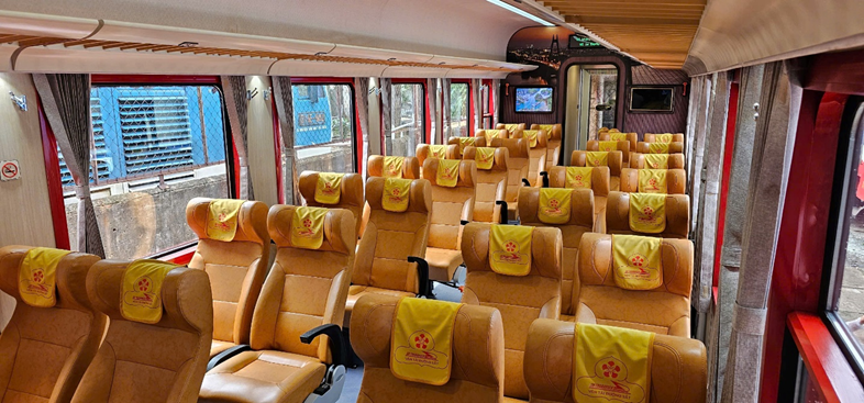 Interior del tren turístico del Hai Van Pass con asientos amplios y fundas amarillas junto a las ventanillas panorámicas