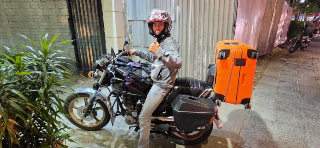Conductor de Le Family Riders con una maleta grande atada a la moto para transportarla por separado al destino